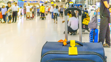 Blue suitcase with yellow tag in airport terminal, holiday vacation travel concepts.