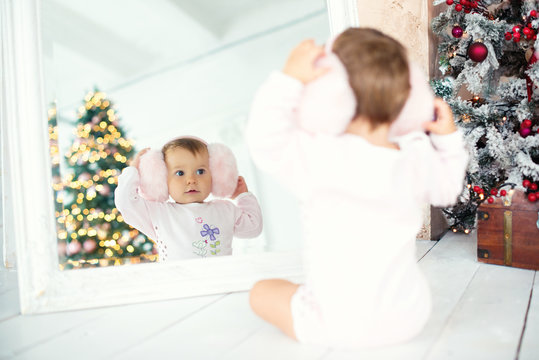 Little girl with headphones looking in the mirror. Christmas mood.