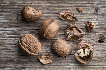 Walnuts on a wooden aged rustic background. Broken, crushed walnuts