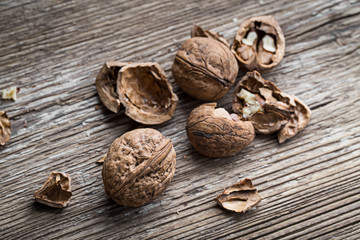 Walnuts on a wooden aged rustic background. Broken, crushed walnuts