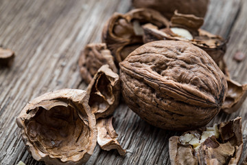 Walnuts on a wooden aged rustic background. Broken, crushed walnuts