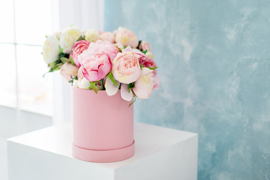 Fototapeta Flowers in round luxury present box. Bouquet of pink and white peonies in paper box near the window.Mock-up of hat box of flowers with free copyspace for text. Interior decoration in in pastel colors.