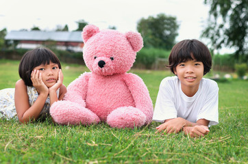 two Little girl with teddy bear and smile on grass in park