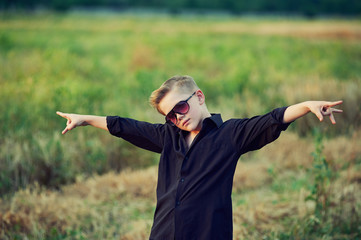 fashionable , stylishly dressed boy posing in nature