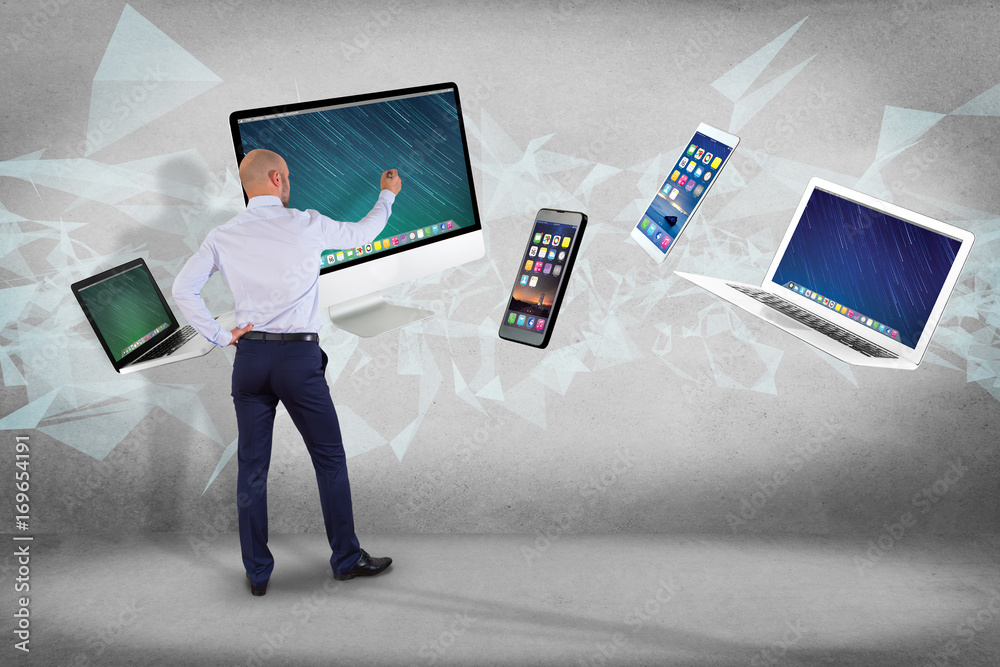 Poster businessman in front of a wall with computer and devices displayed on a futuristic interface with in