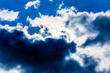 White fluffy clouds in the blue sky. Dramatic cloudscape with sun rays
