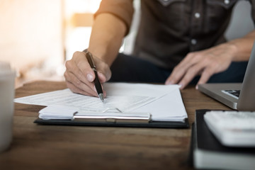 A working wooden desk(table) with notebook computer, coffee cup, paper, pencil and hand