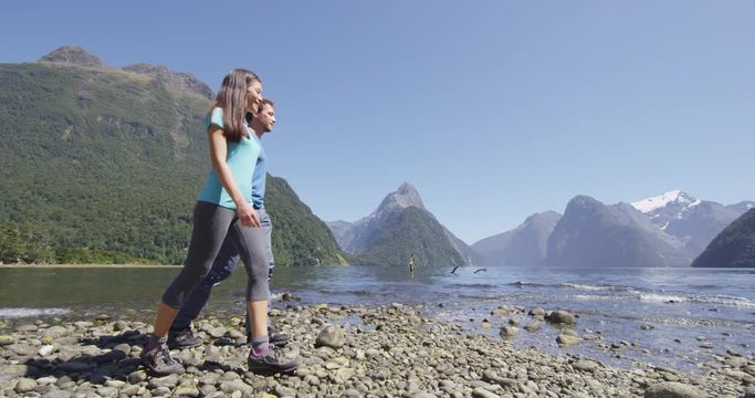 Tourists hiking in New Zealand in Milford Sound by Mitre Peak in Fiordland. Couple on New Zealand travel visiting famous tourist destination and attraction on south island, New Zealand.