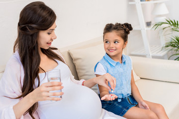 Girl holding out pills to mother