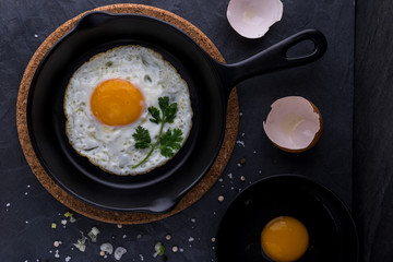 fried egg in black pan and ingredient on dark background