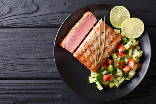 Freshly cooked grilled tuna steak with avocado cucumber salsa close-up. horizontal view from above