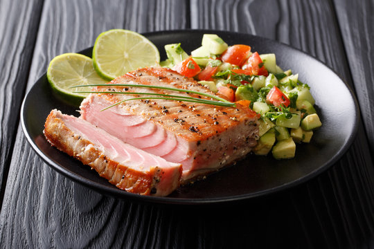 Grilled tuna steak with pepper and avocado cucumber salsa close-up. horizontal