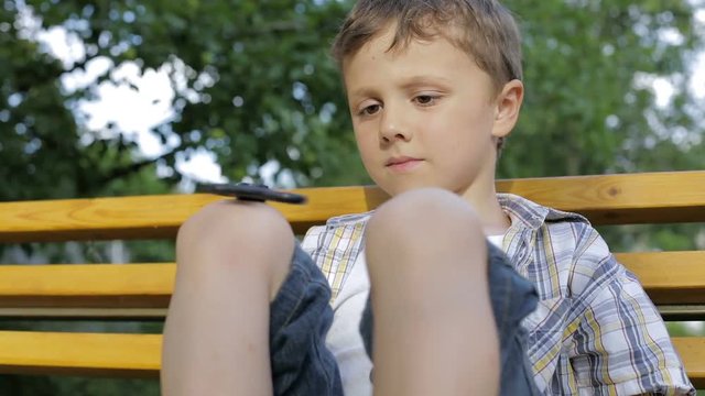 Happy little boy playing in the park at the day time. He playing with spinner. Kid having fun on the nature. Concept of happiness.