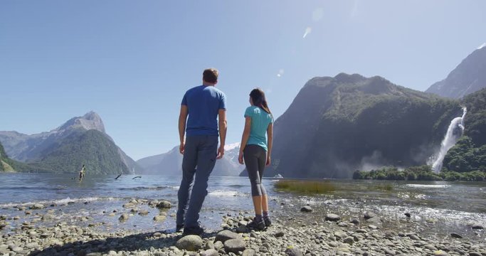 New Zealand - tourists hiking standing looking at Milford Sound enjoying iconic view and famous tourist destination and landmarks in Fiordland National Park, South Island, Southern Alps, New Zealand.