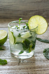 Mojito cocktail with lime and mint in highball glass on a white wooden background