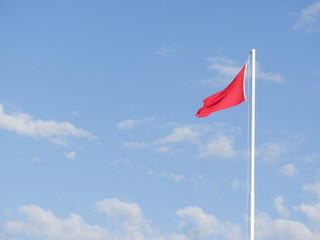 red flag for rough sea over a lifeguard tower long an Italian beach