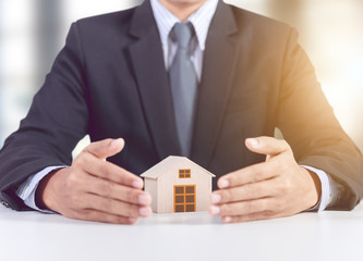 Fototapeta na wymiar businessman hand cover wooden home model, insurance concept