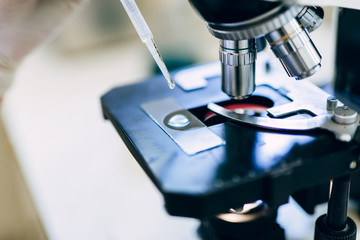 Unrecognizable worker or scientist working with microscope in laboratory