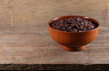 Luem Pua or Black sticky rice in a wooden bowl on an old wooden floor.