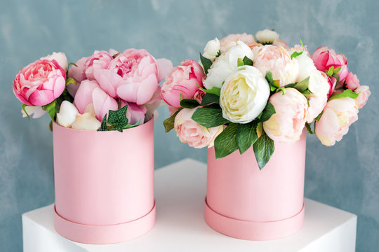 Flowers in round luxury present boxes. Bouquet of pink and white peonies in paper box. Mock-up of hat box of flowers with free copyspace for text. Interior decoration in in pastel colors.