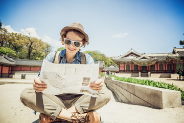 Young woman tourist with map in hand on the background of Asian architecture, travel to Korea, Seoul Asia