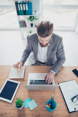 Vertical photo of busy young worker trying to search some information in the internet while having a snack at light modern work place