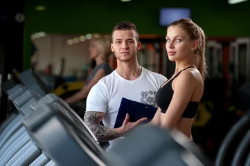 Foto op Plexiglas Cute female working out with fitness coach in gym © pavel_shishkin