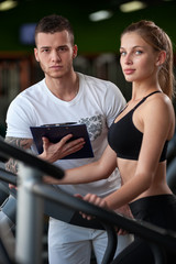 Blonde female working out in gym with coach