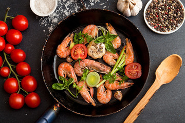 Bbq grilled shrimps on fried pan serving with cherry tomato, basil, leek and baked garlic. Barbecue seefood concept. Top view.