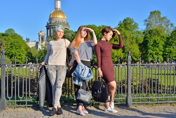 Obraz premium Three young girls thoughtfully standing at the iron fence on the background of St. Isaac's Cathedral in Saint-Petersburg