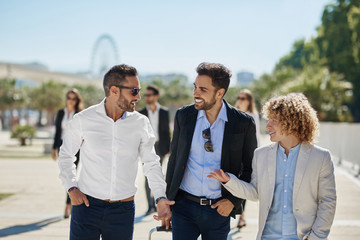 Three happy businessmen having conversation outside