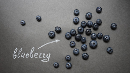 Top view of blueberries on chalkboard with text. Macro. 