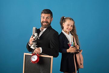 Man with beard and girl in uniform. Teacher and schoolgirl