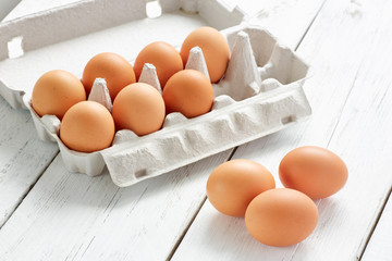 Cardboard egg rack with eggs on white wooden table