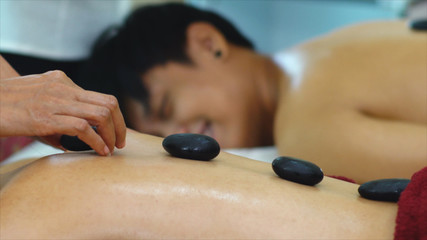 Thai masseur place the hot stone on backbone of woman