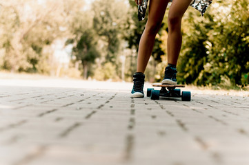 Closeup legs of girl riding modern skateboard on city street