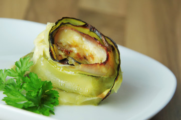 Roll of zucchini roasted with cheese and ham. Wooden background. Close up view.