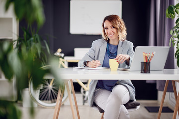 Businesswoman in early thirties working at home while sitting in personal work space 