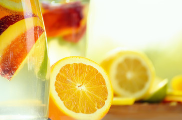 Glass bottle with a fruit drink with pieces of half an orange close-up . Summer mood, a useful drink.
