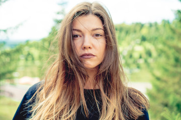 young brown wild haired woman student enjoys in park sunny weather