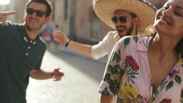 Multirace interracial mexican theme party concept - attractive turkish latina european people dancing on the city street, lens flare sun shining, sunglasses tequila sombrero lens flare shining sun