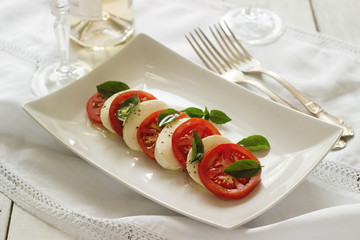 Caprese salad with ripe tomatoes and mozzarella cheese with fresh basil leaves. Italian food.