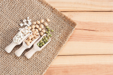 Whole grains in wood scoop on wooden table.