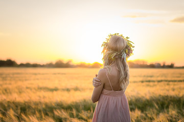 Fototapeta na wymiar portraits of young woman having good time in wheat field during sunset, lady in head flower wreath during 