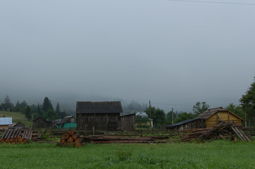 Fototapeta premium Wioska jest w górach. Domy drewniane, mgła, góry