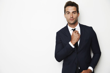 Confident businessman adjusting tie, portrait