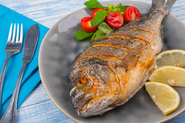 Grilled dorado on plate and wooden Background
