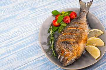 Grilled dorado on plate and wooden Background