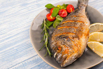 Grilled dorado on plate and wooden Background