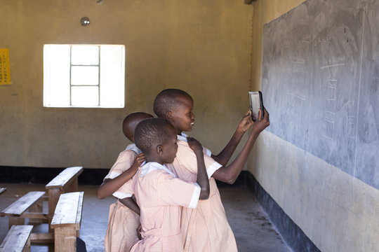 School girls using tablet in classroom. Kenya, Africa.